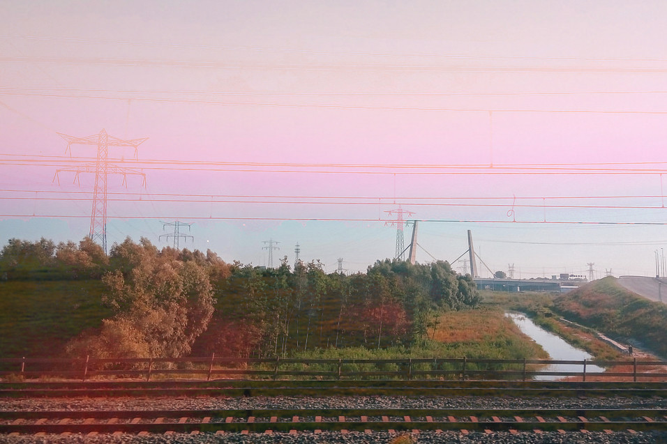 Double exposure of flat Dutch landscape and railway lines under pale pink sky, digital collage