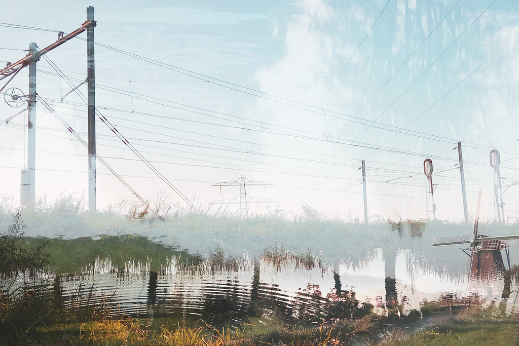 Layered double exposure of polder landscape, power pylons and windmill in mist, Netherlands